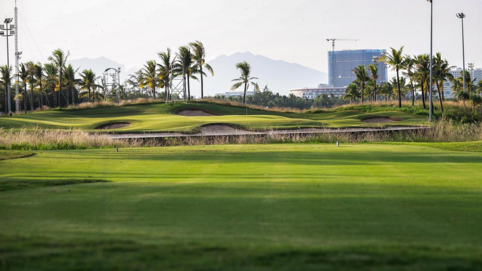 A smooth green nestled with sand bunkers and city views in the distance