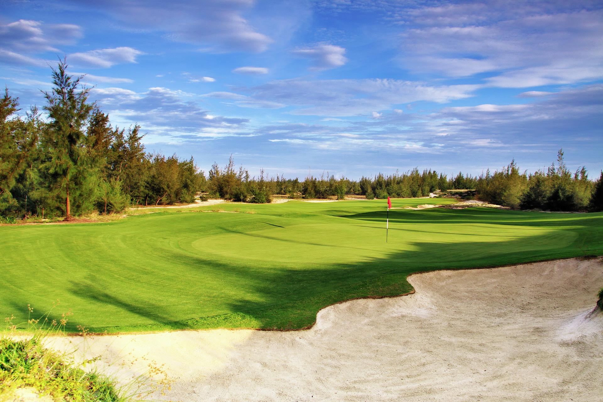 A large sand bunker strategically placed by a manicured green at the BRG Da Nang Golf Resort