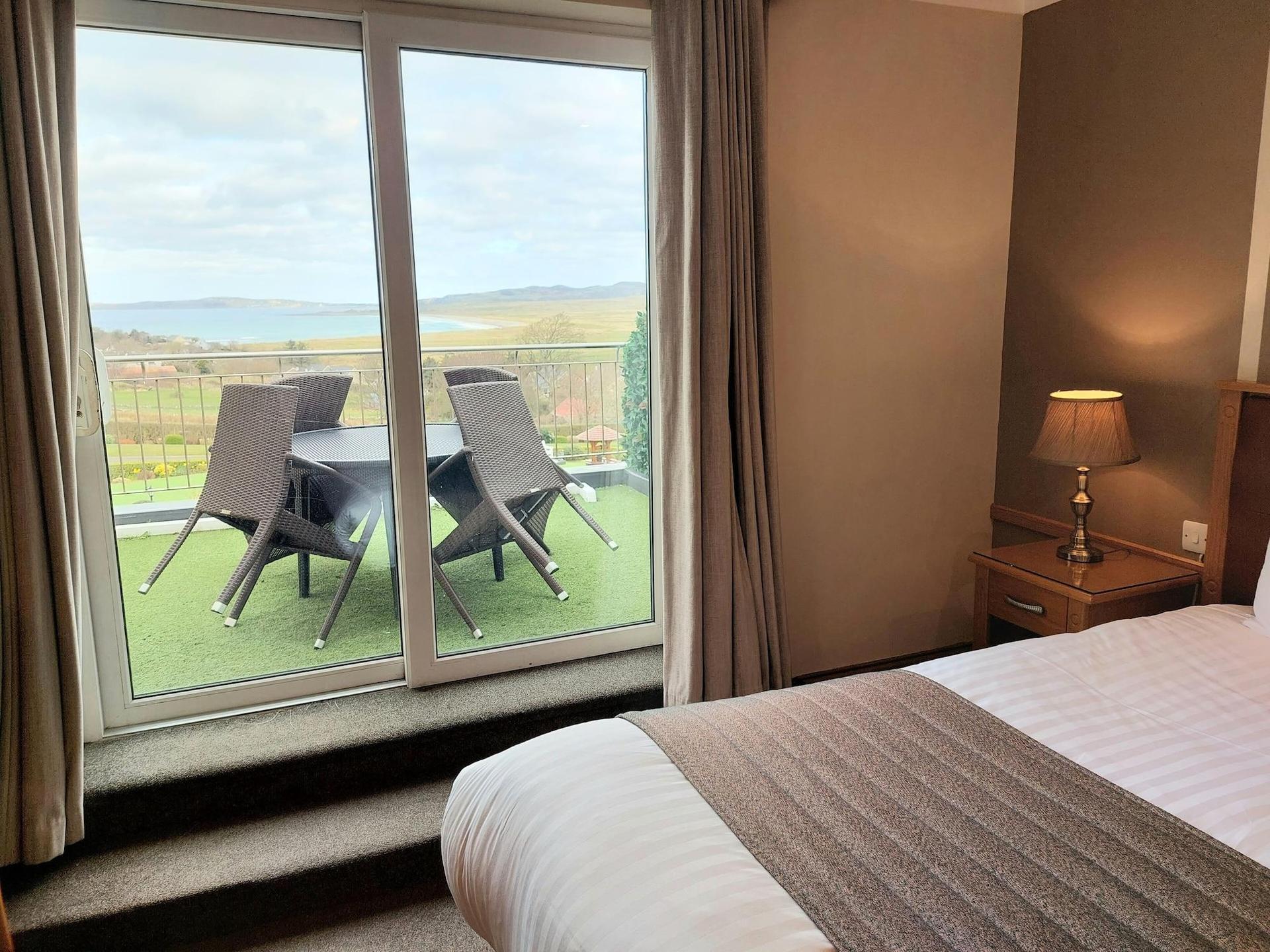 Brown themed modern bedroom with a balcony overlooking the landscape and sea