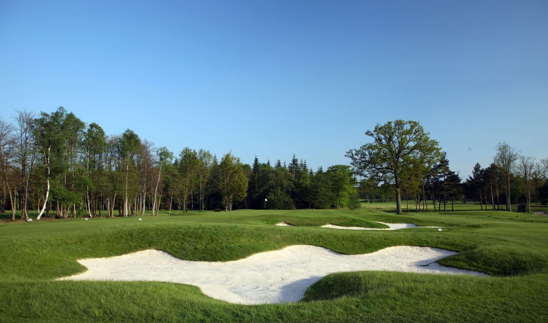 Uniquely shapes sand bunkers located next to the green under clear blue skies at the Bracken course
