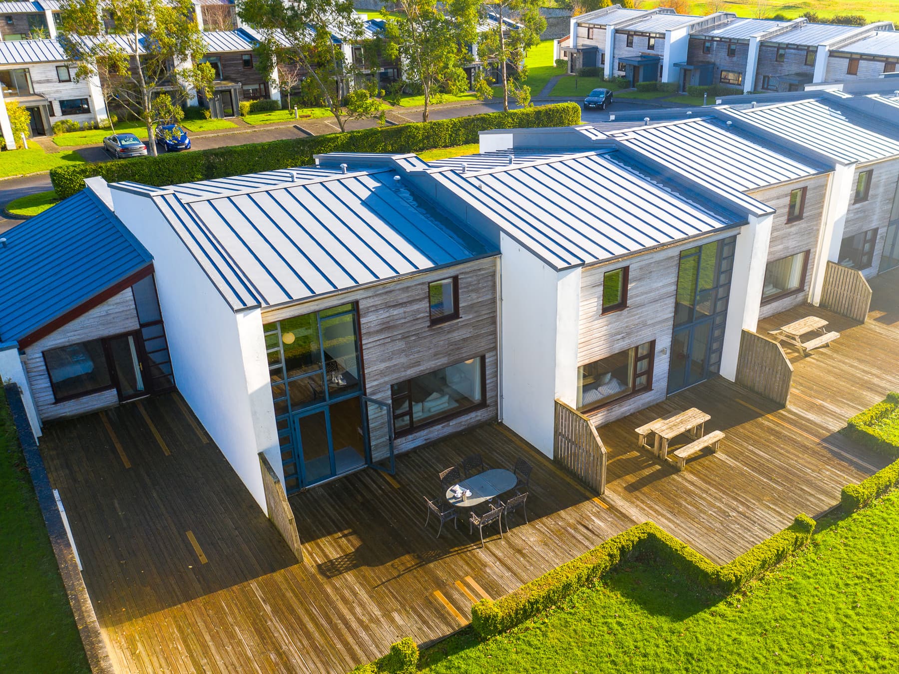 Contemporary resort villas with private outdoor terraces overlooking lush green lawns.