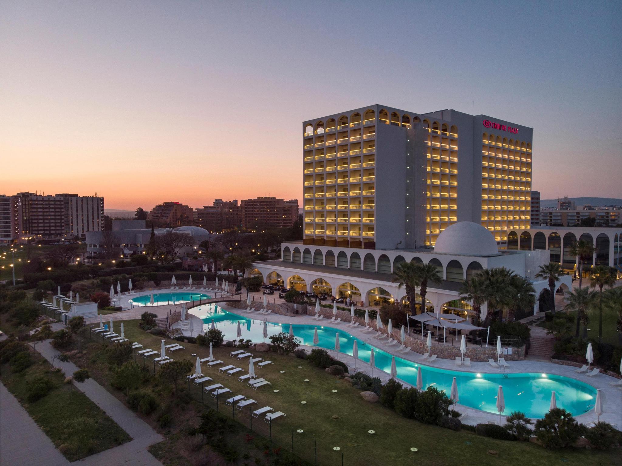 Outside view of the Crowne Plaza Vilamoura at dusk with swimming pool visible