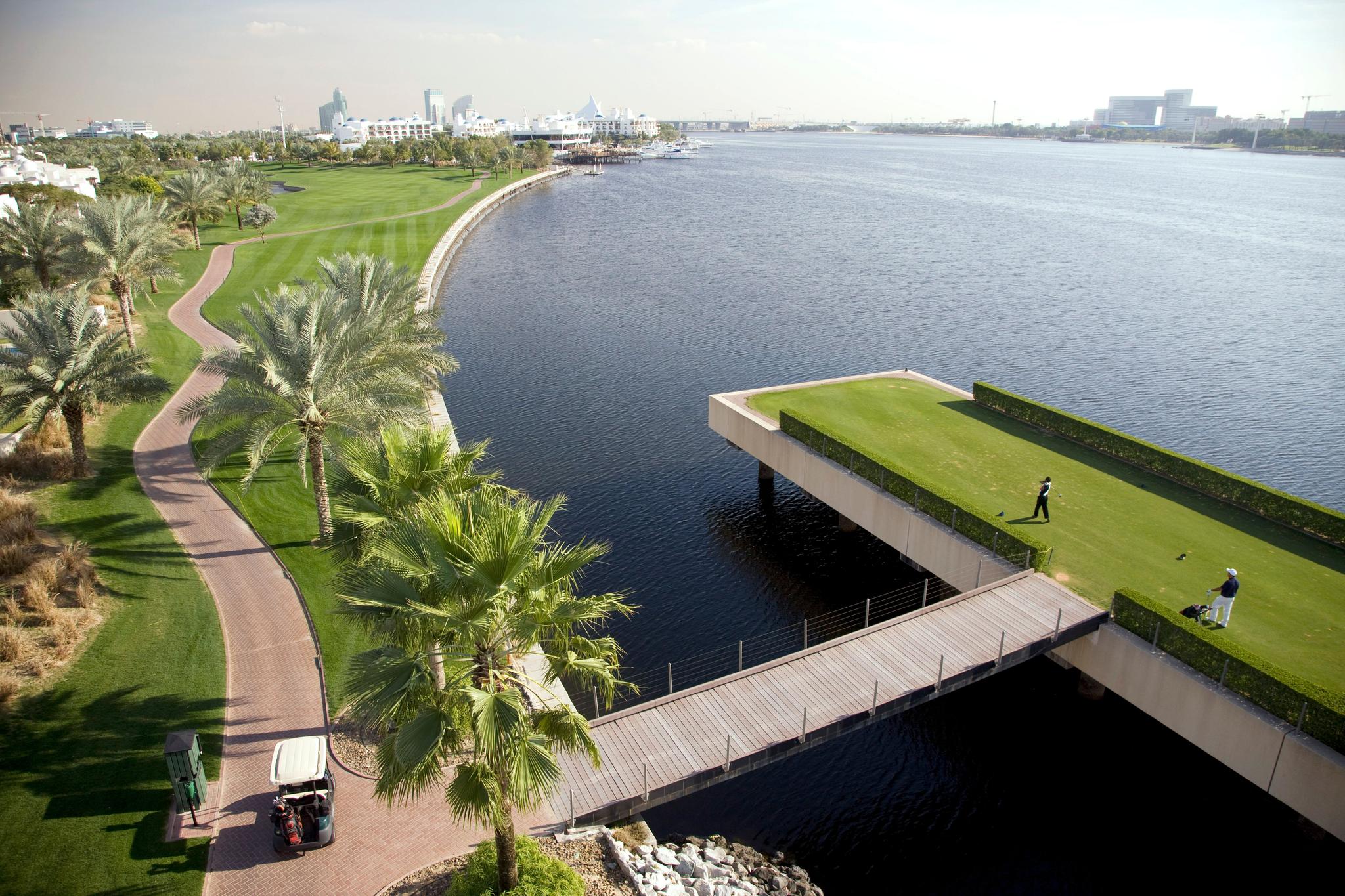 An island tee box with a bridge to navigate the course at the Dubai Creek Golf Club