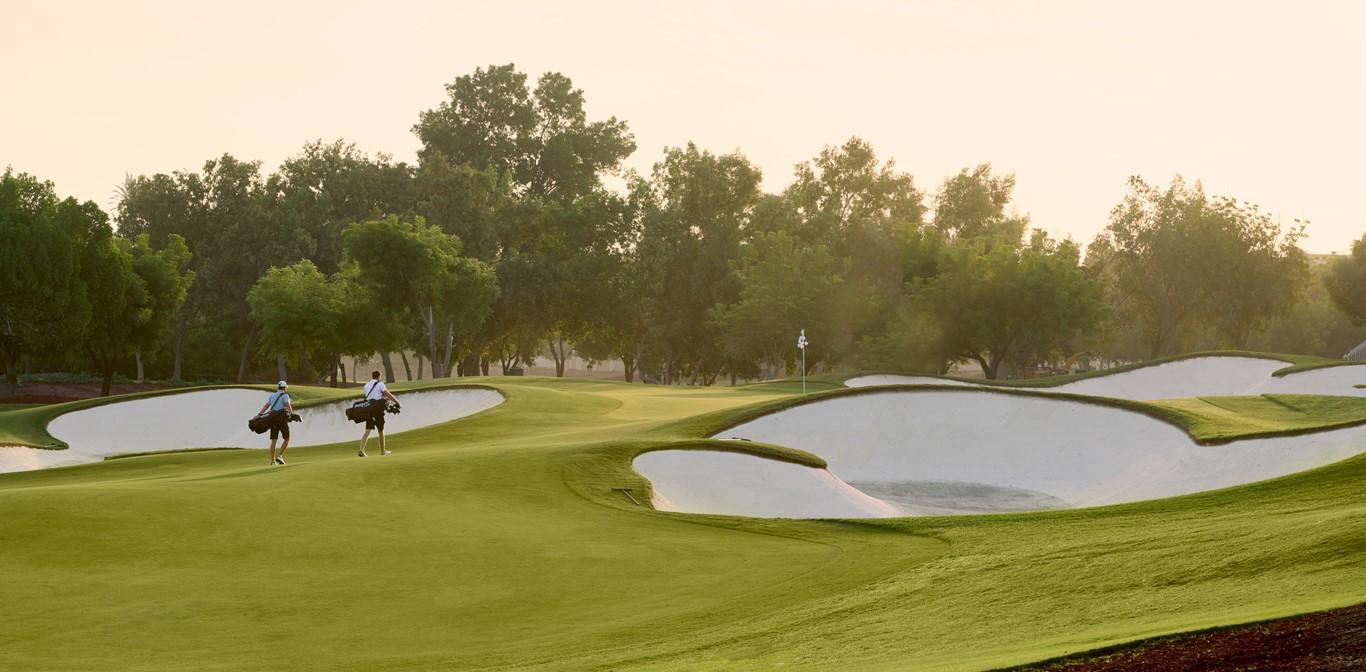Dubai Earth Golf Course fairway surrounded by trees on a sunny day