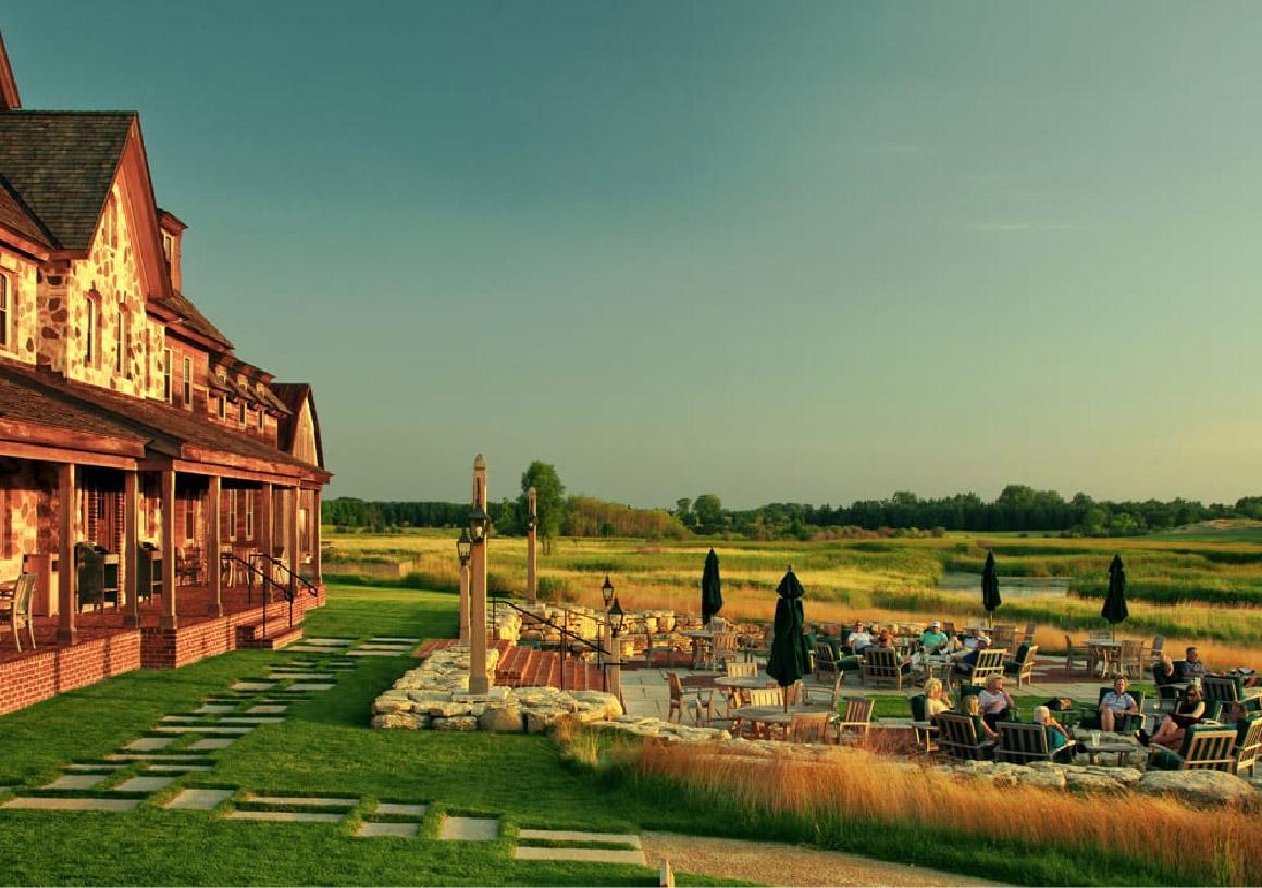 The Erin Hills clubhouse overlooking the course and an outdoor seating area for guests to lounge