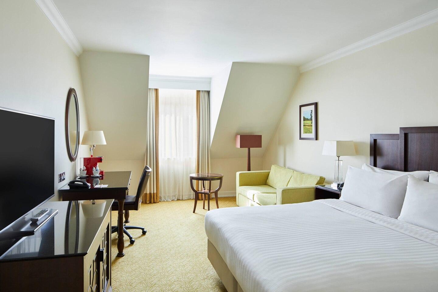 Spacious double bed suite with a sofa for lounging, smart tv, work desk and window for natural light