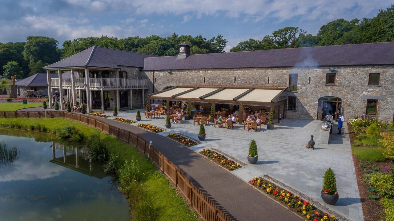 Stone building with outdoor dining by a peaceful pond.