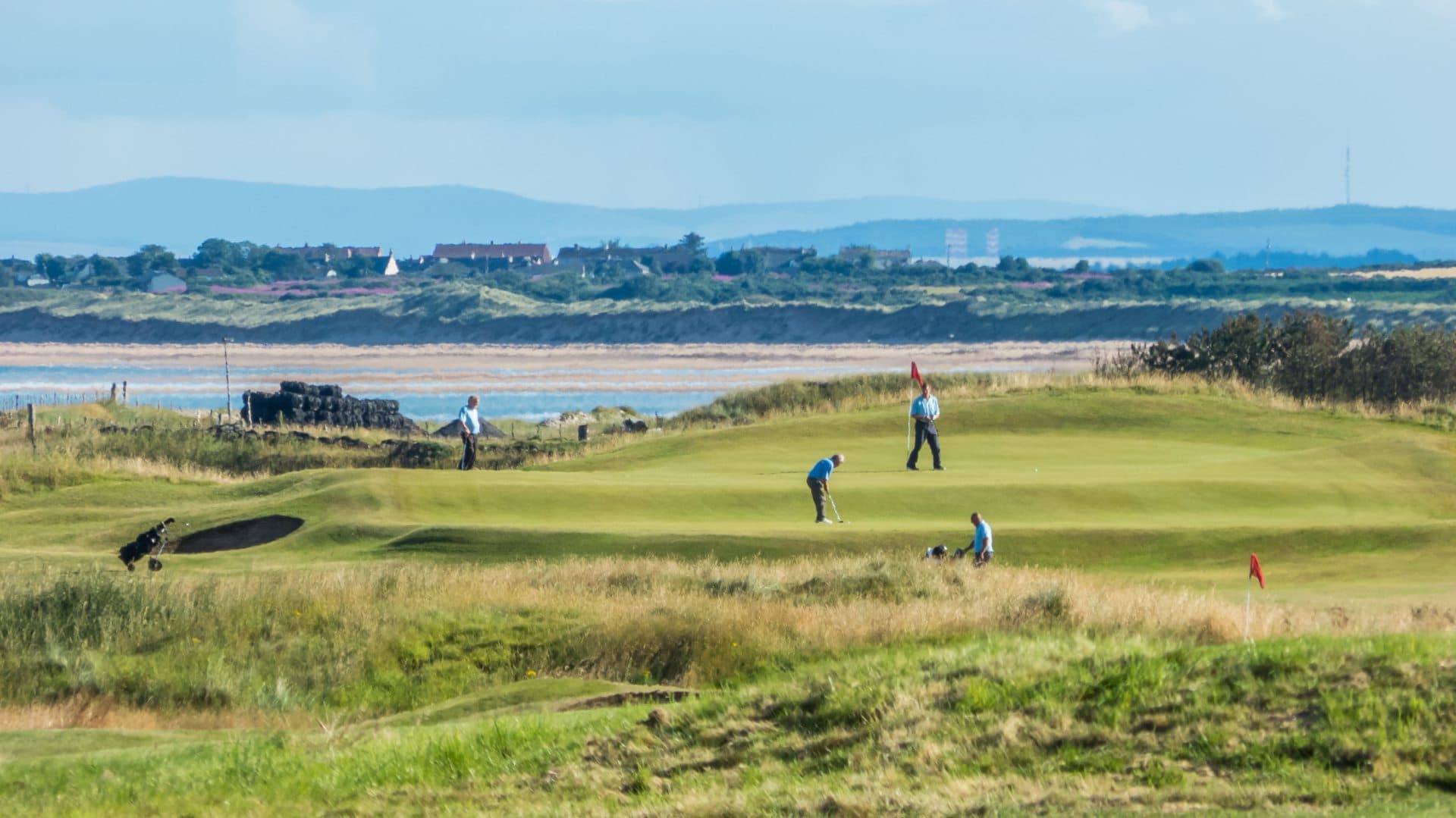 Golfers enjoying their round of golf at the Golspie course with sea views in the back