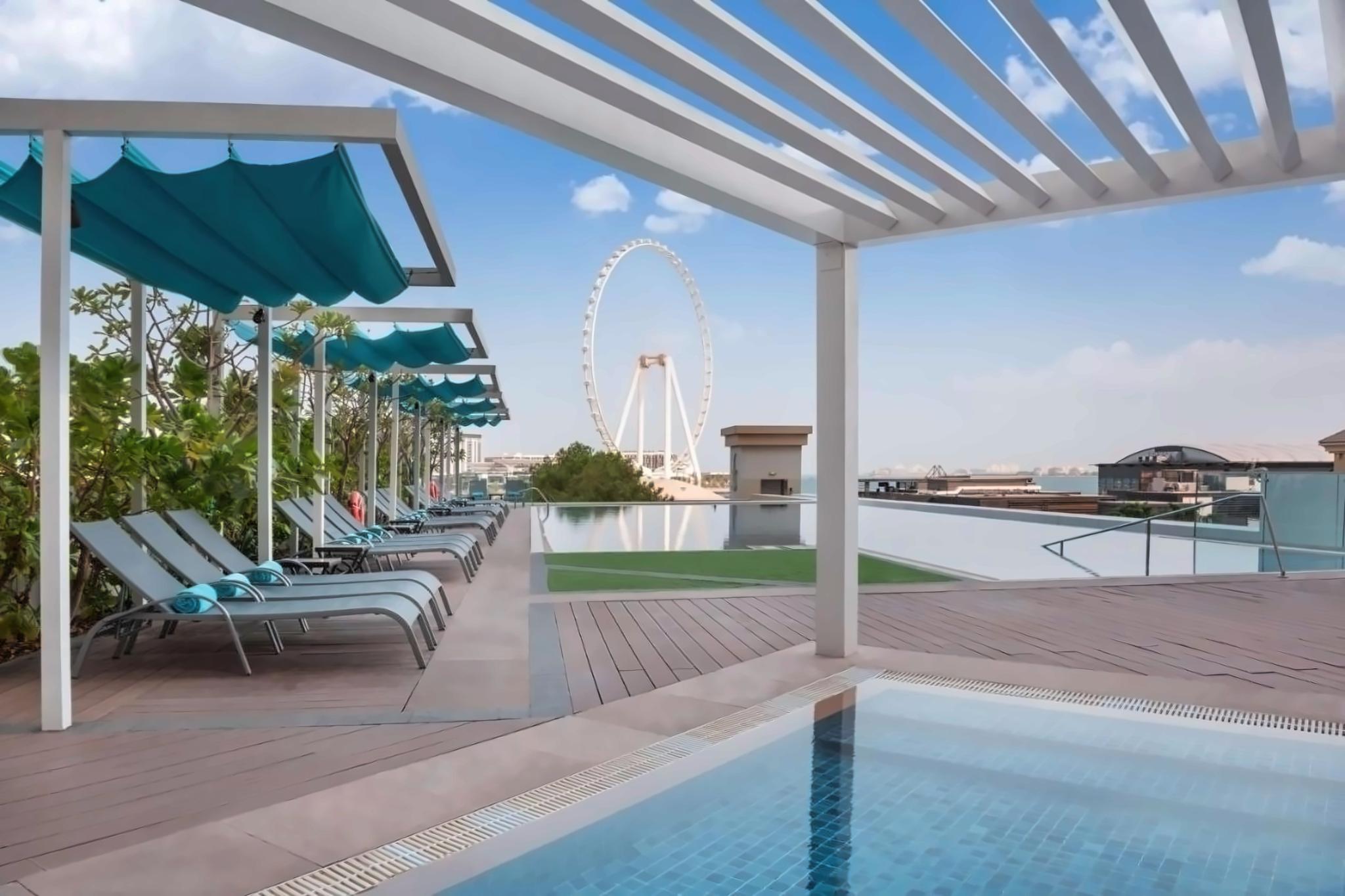 Rooftop swimming pools at the hotel surrounded by sunbeds under clue skies