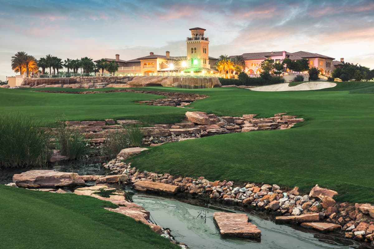 The Jumeirah Golf Estates clubhouse overlooking a smooth green nestled with a large sand bunker