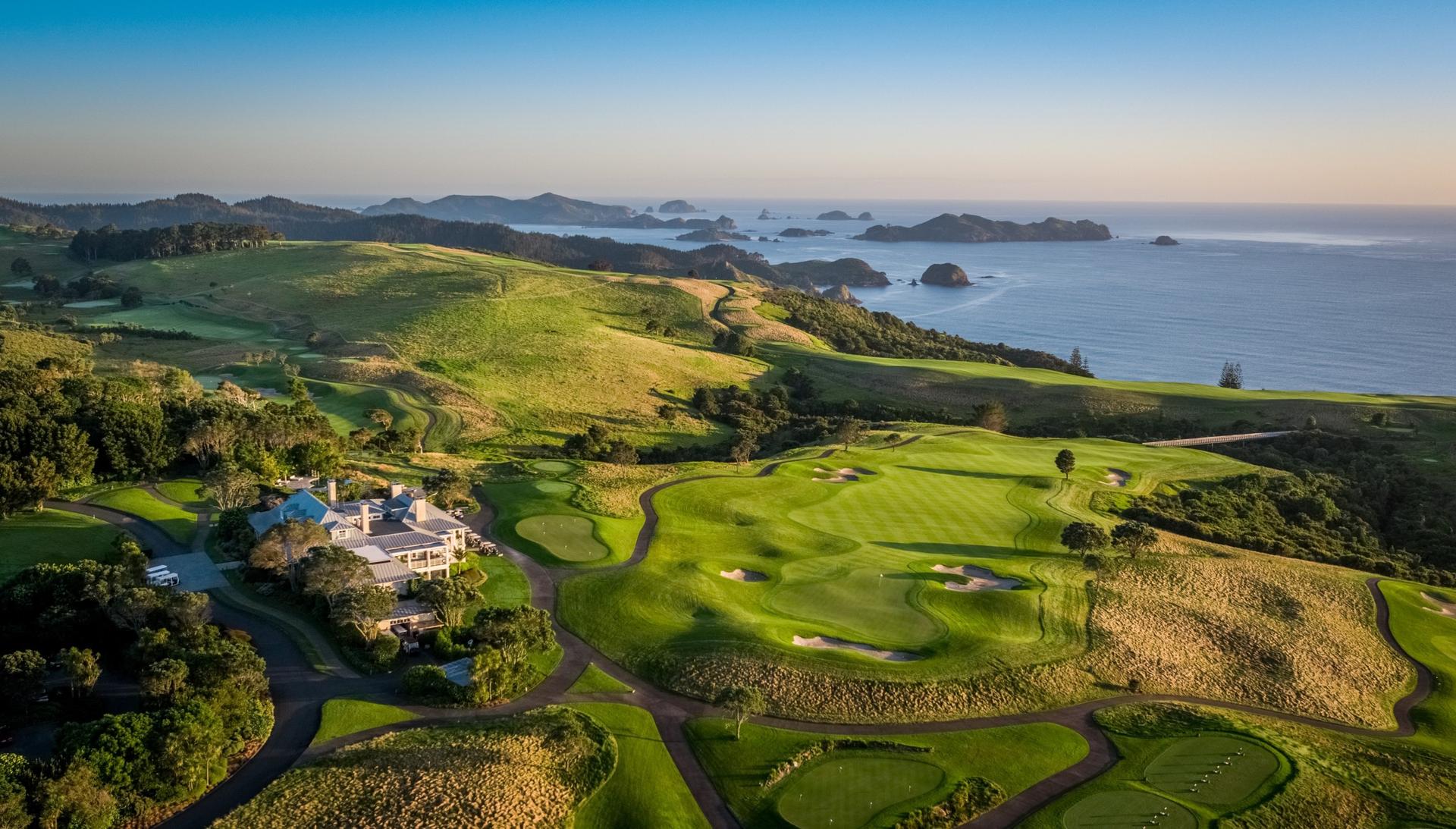 A wide fairway leading to a smooth green nestled with sand bunkers just outside the clubhouse