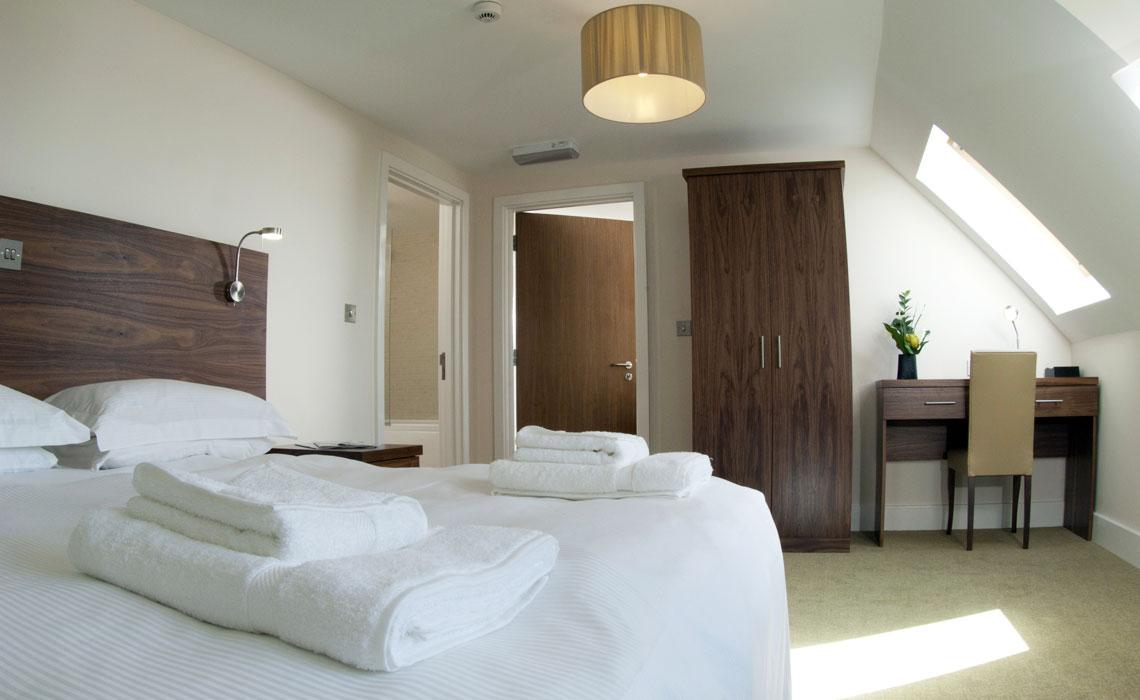 Modern double bed room with a wooden design and natural light coming through windows