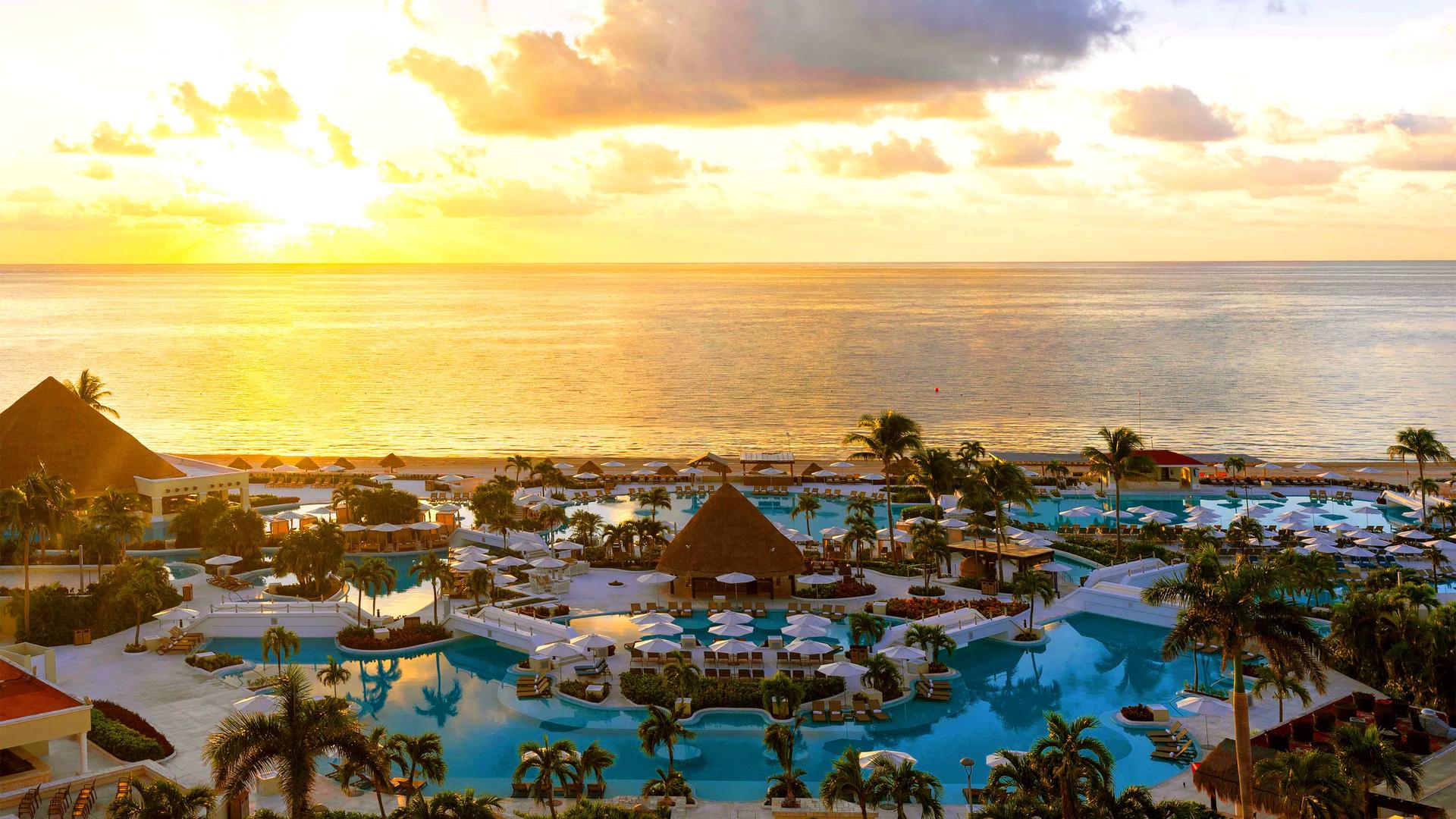 Sun setting over the Moon Palace Resort's expansive swimming pool with sea views