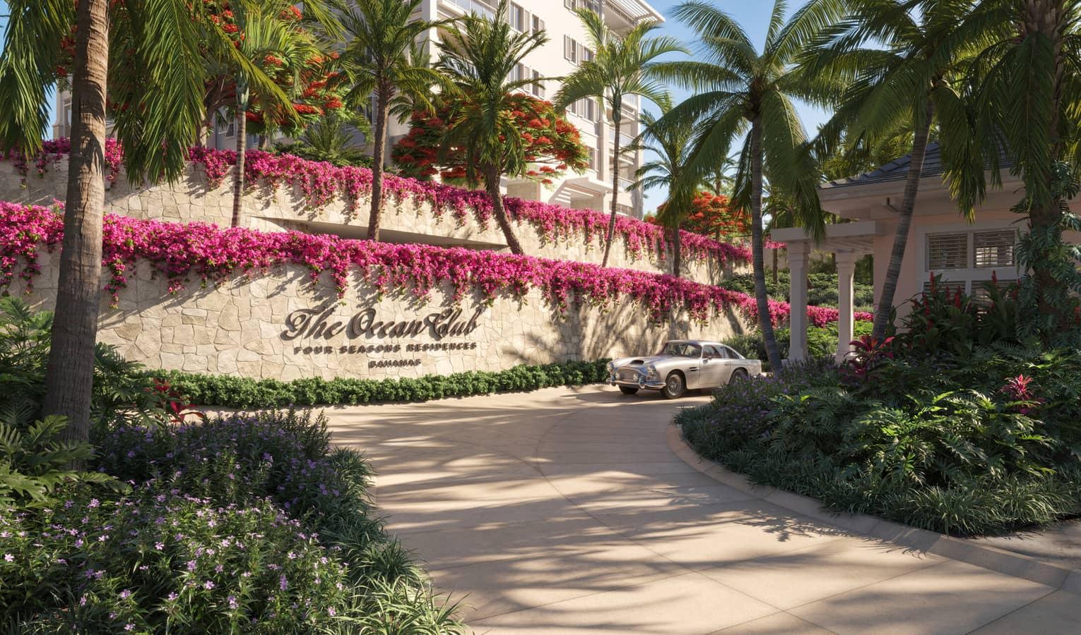 Driveway into The Ocean Club resort with their sign on the wall decorated with pink flowers