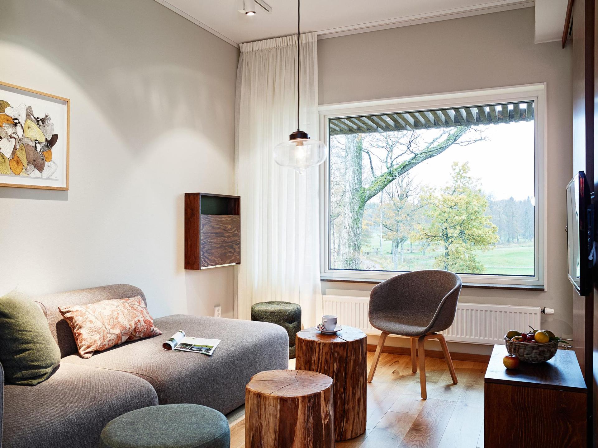 A cozy modern lounge with a large window view of trees and a golf course.