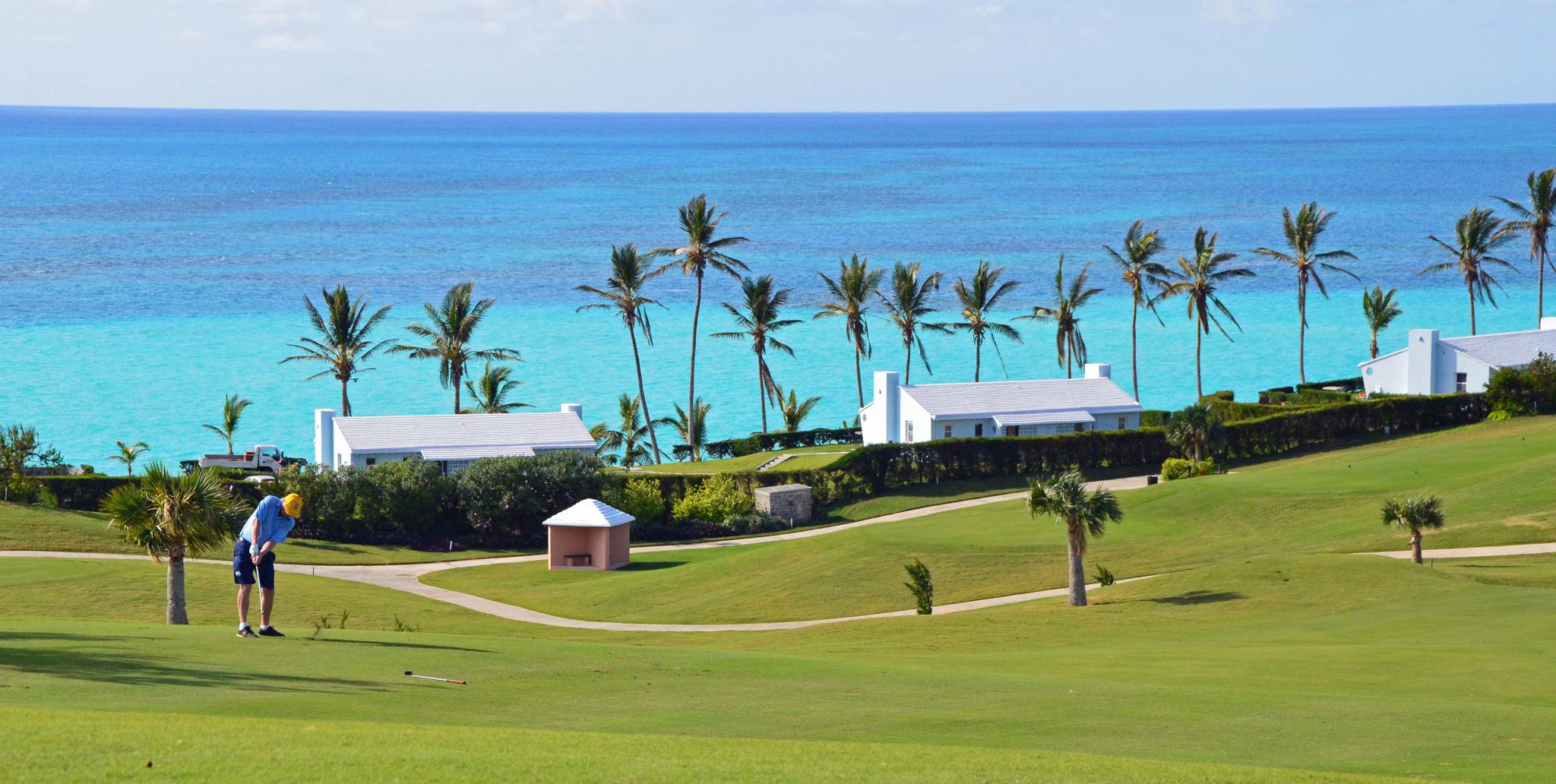 Gentleman playing his round of golf with sea views framed by palm trees