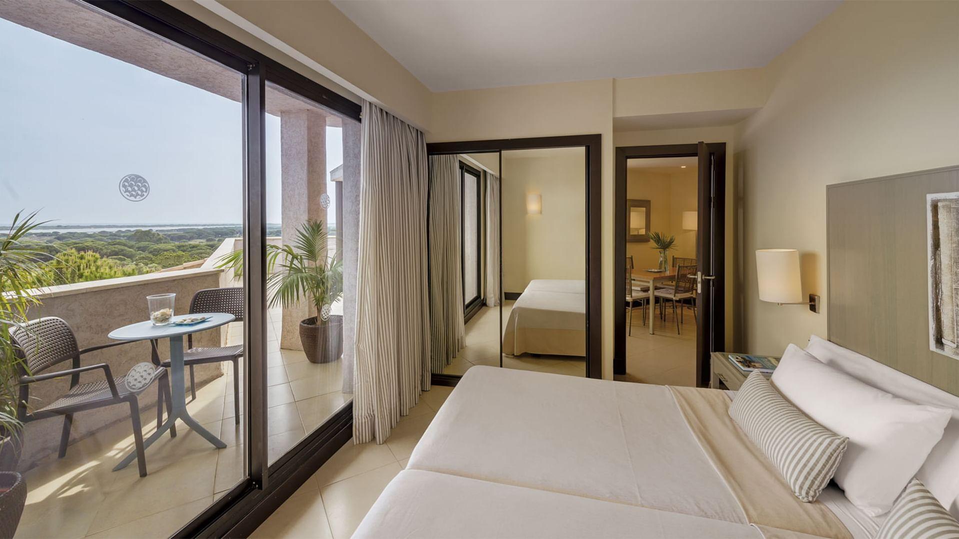 Double bed and living/dining room set up with balcony in a suite