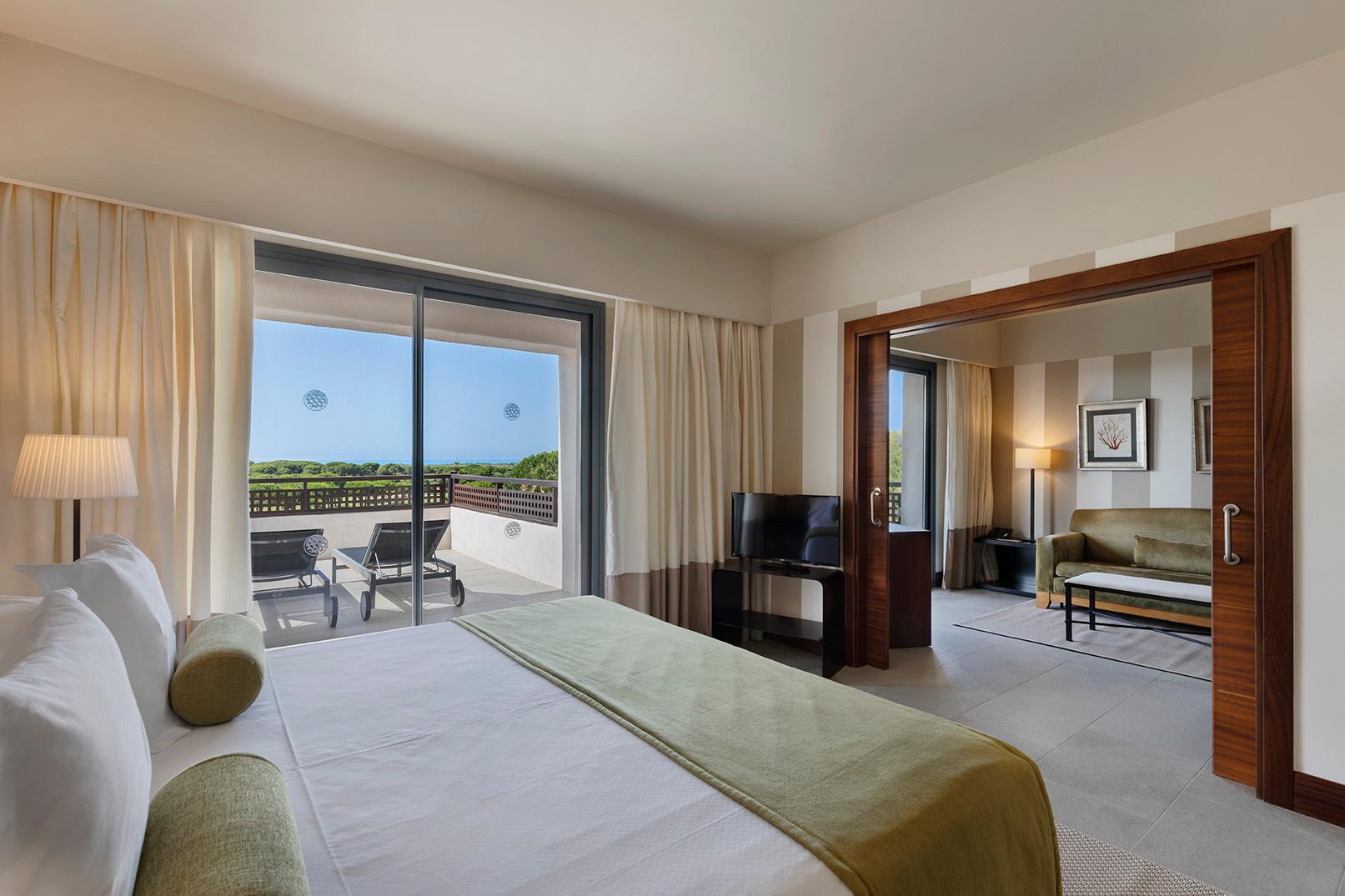 Double bed with living room set up and balcony in a suite