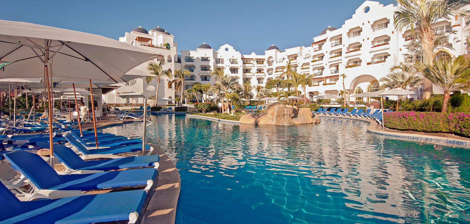 Outdoor swimming pool at the hotel surrounded by sunbeds and umbrellas