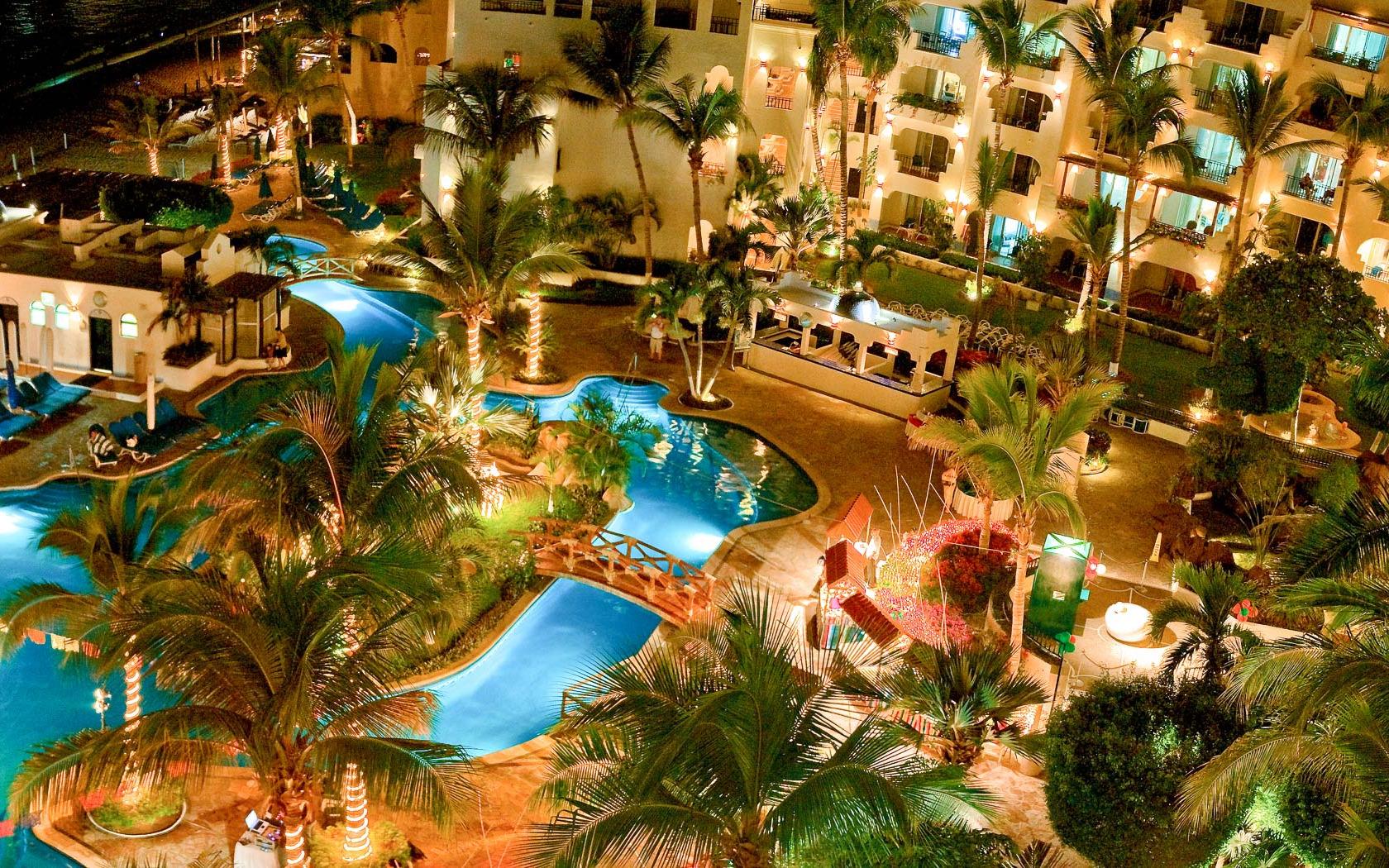 Overhead view of the outdoor swimming pool at night being lit up by the resorts lights