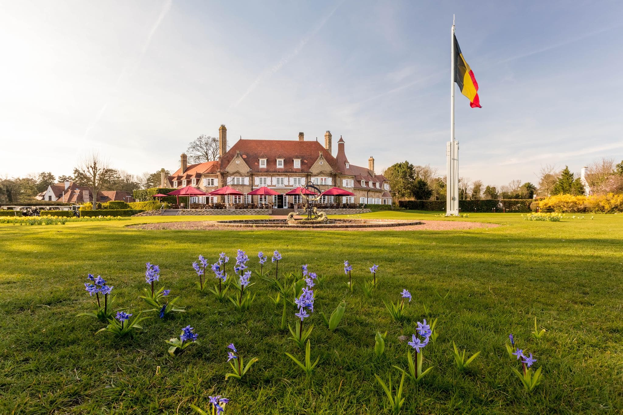 The Royal Zoute clubhouse with outdoor seating and the Belgium flag swaying in the wind