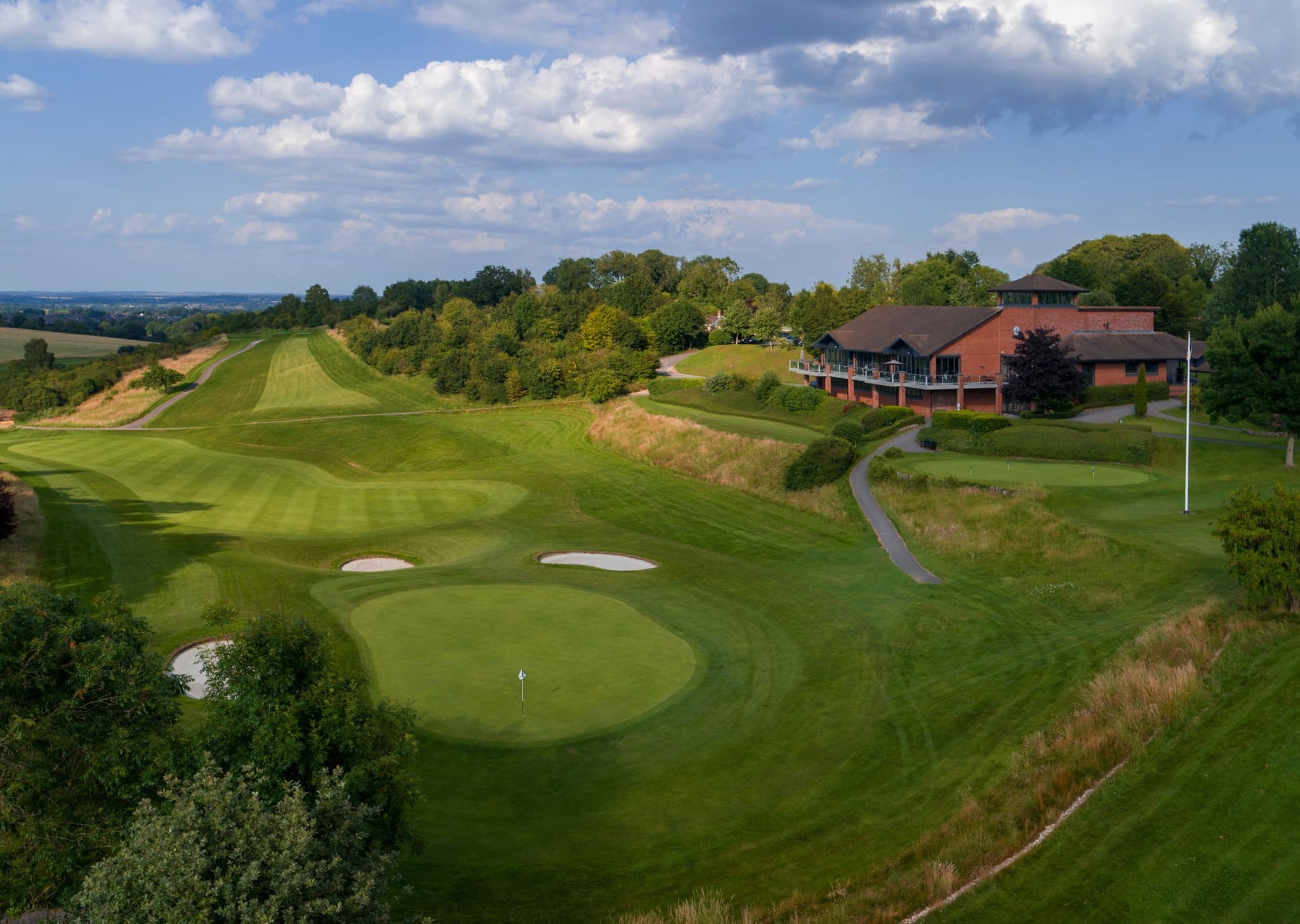 A wide straight fairway leading to a well-maintained green surrounded by sand bunkers