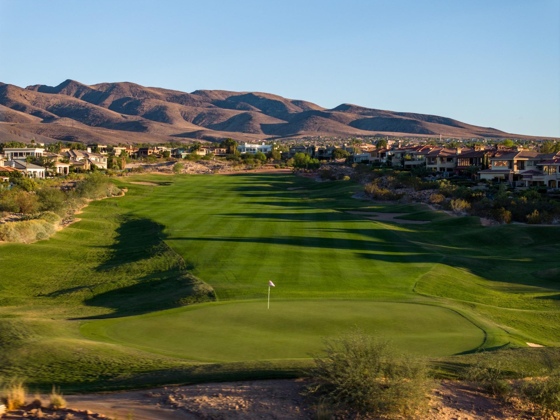 A wide, well-manicured fairway at Serket Golf Club surrounded by upscale desert homes.