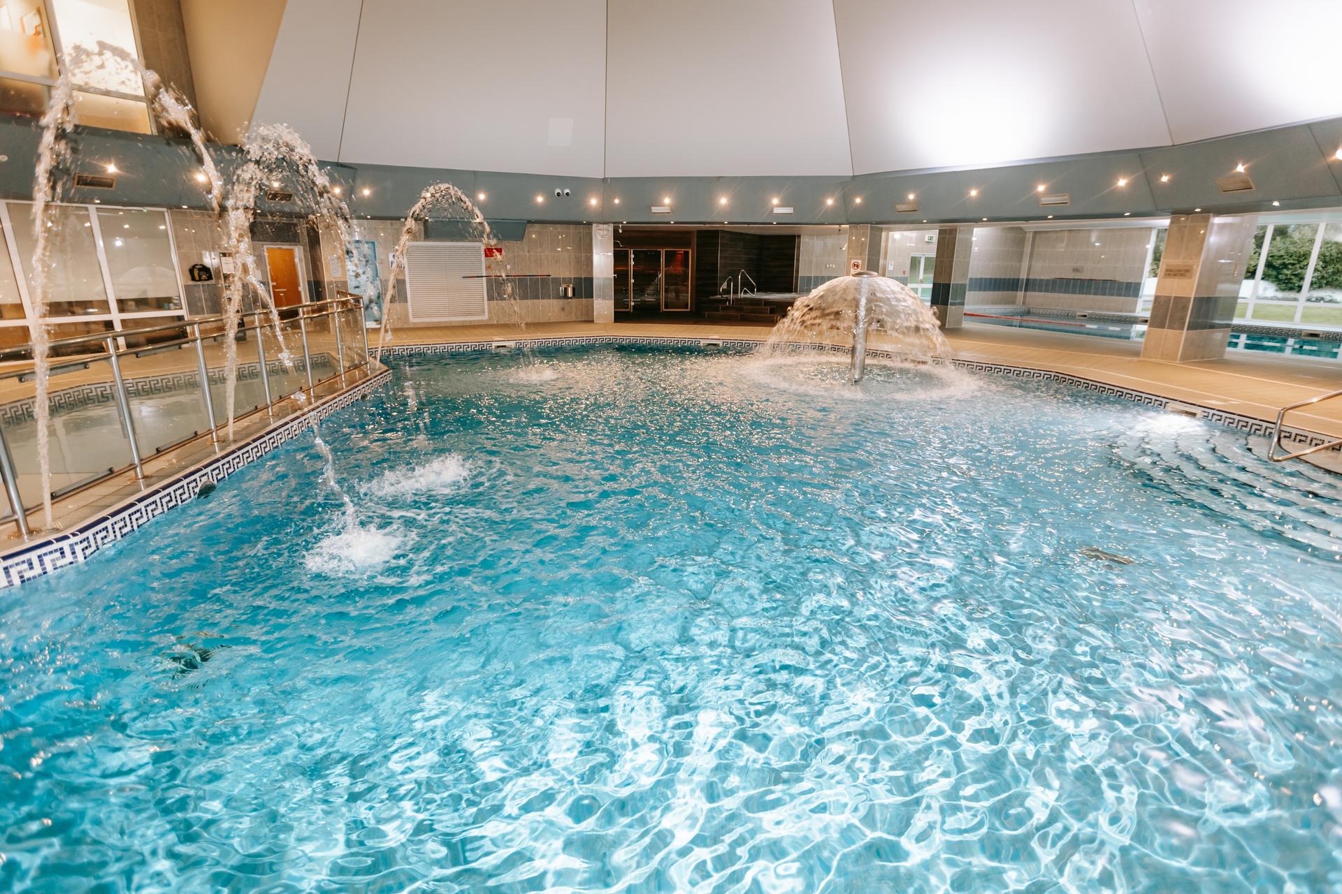Indoor swimming pool with water fountains, another pool with lanes, a jacuzzi and sauna