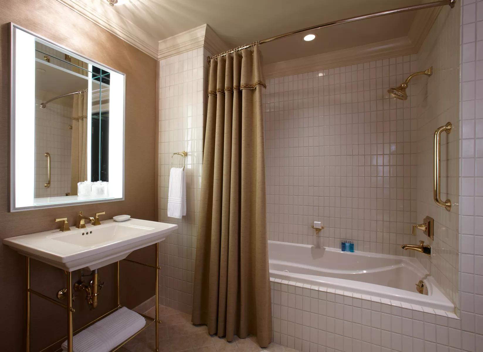 A modern bathroom with a bathtub and gold fixtures.
