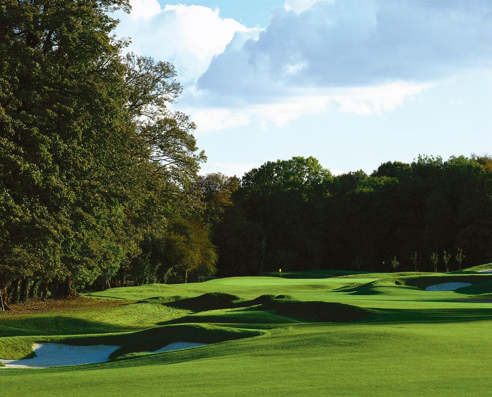 Rolling dunes nestled with sand bunkers leading to the green under blue skies