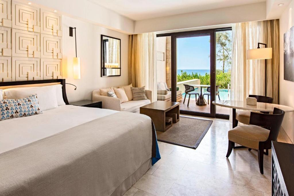 Double bed room at The Romanos Resort with patio seating alongside a personal pool