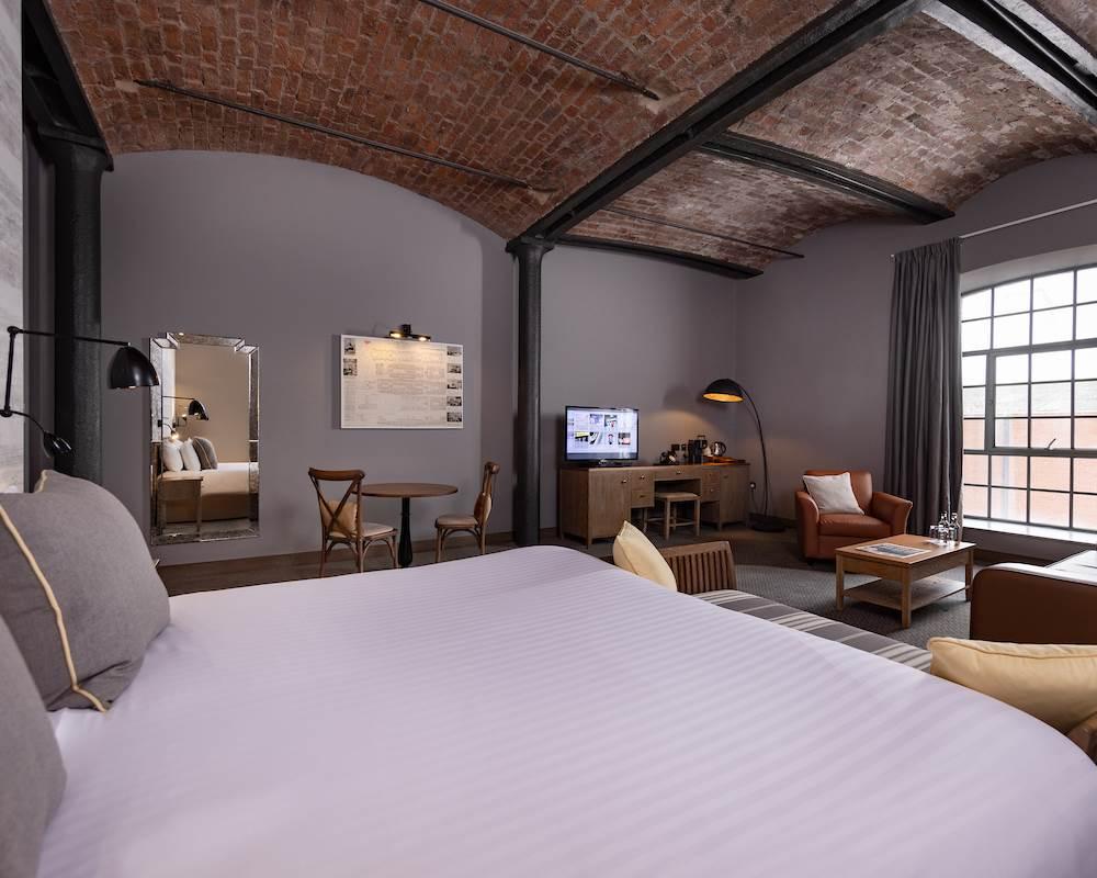 Stone brick ceiling looking over the double bed suite at the Titanic Hotel with lounging area, Tv and panoramic window.