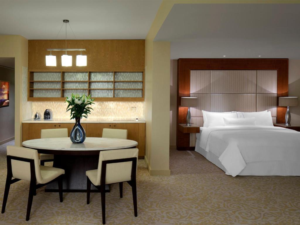 A modern double bed suite at the resort with a dining table and kitchen area