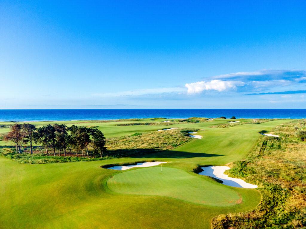 A wide fairway leading to a well maintained green surrounded by sand bunkers