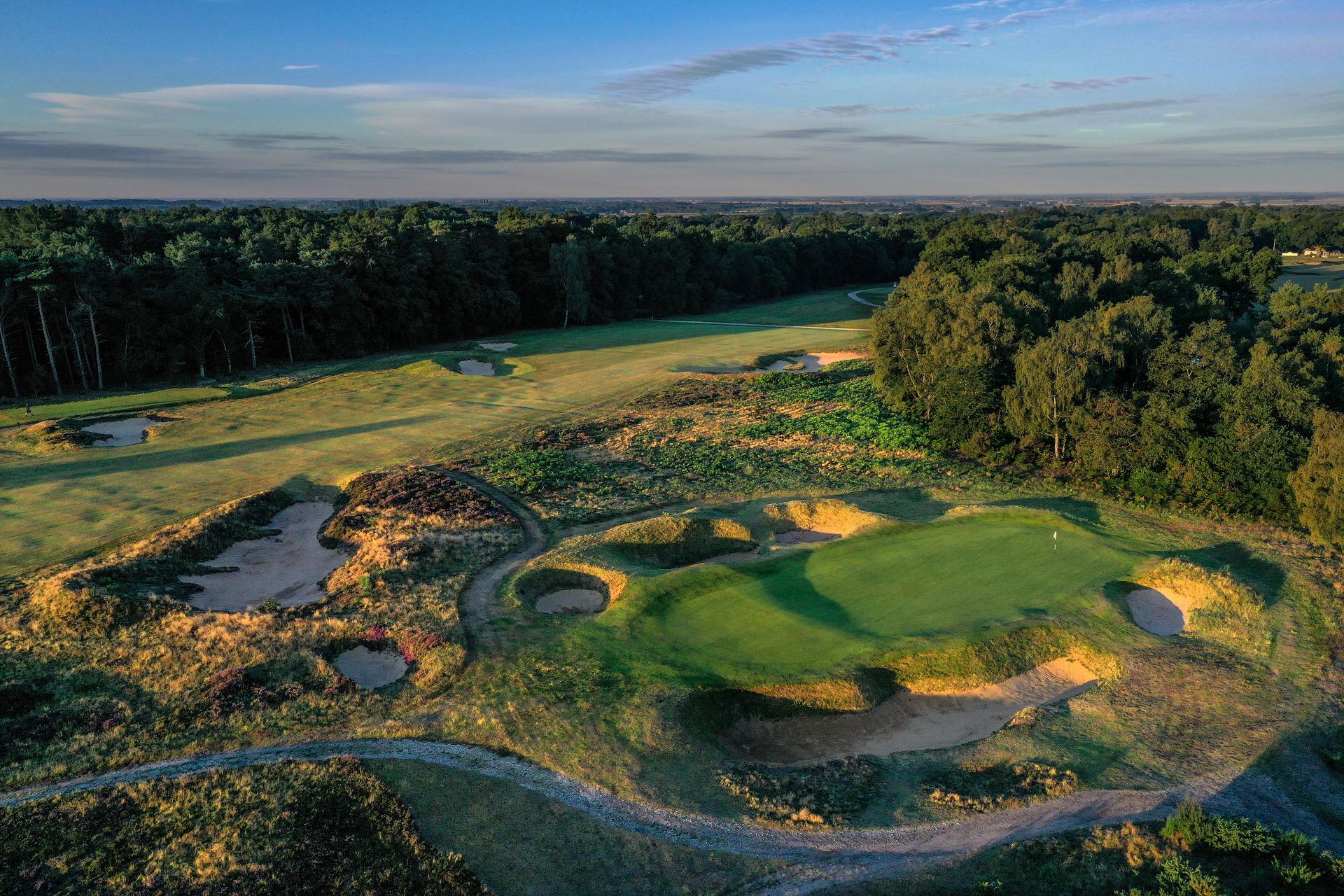 Green with rugged bunkers and forest backdrop.