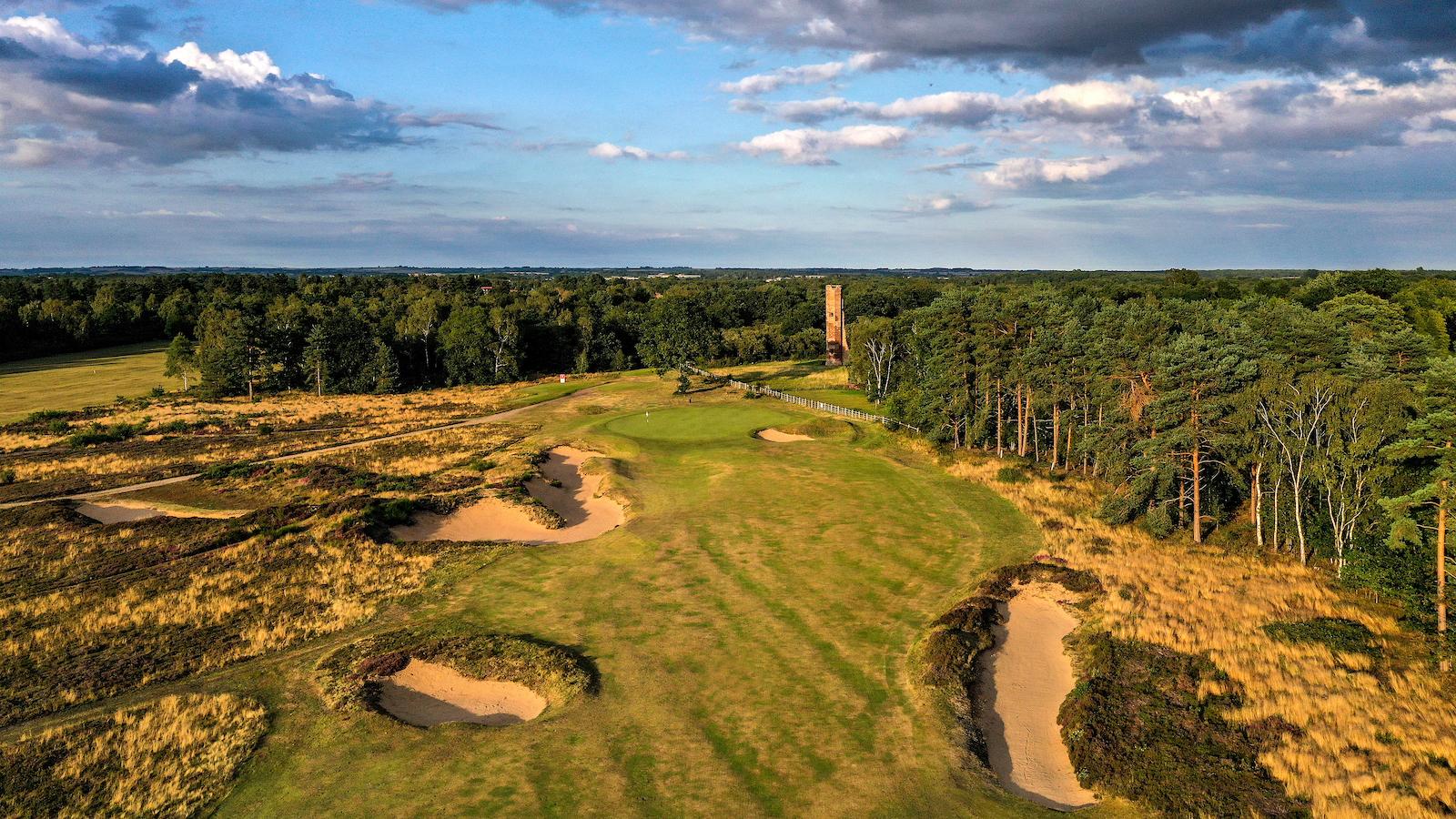 Fairway with deep bunkers and a tall tower in the distance.
