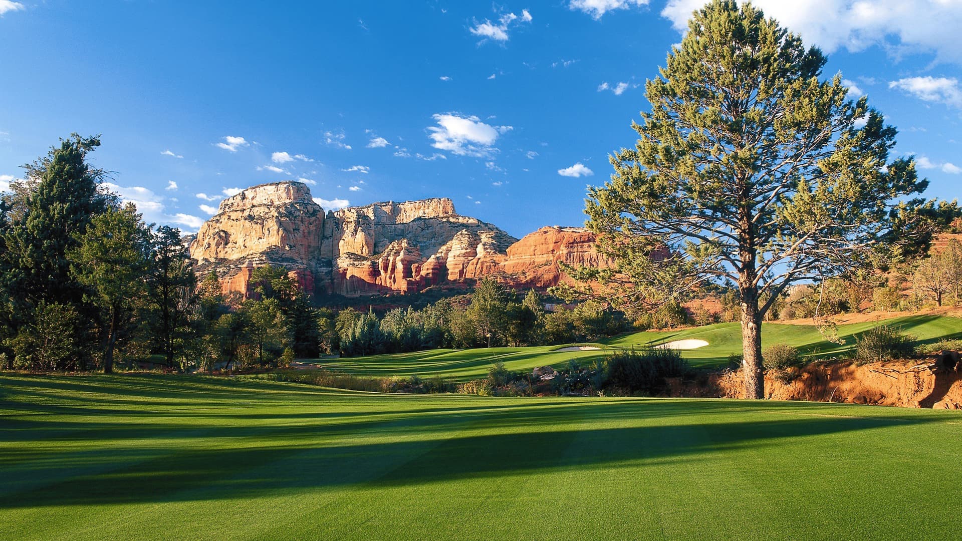 Extreme mountains looking over a well maintained green on the Sedona course nestled with sand bunkers