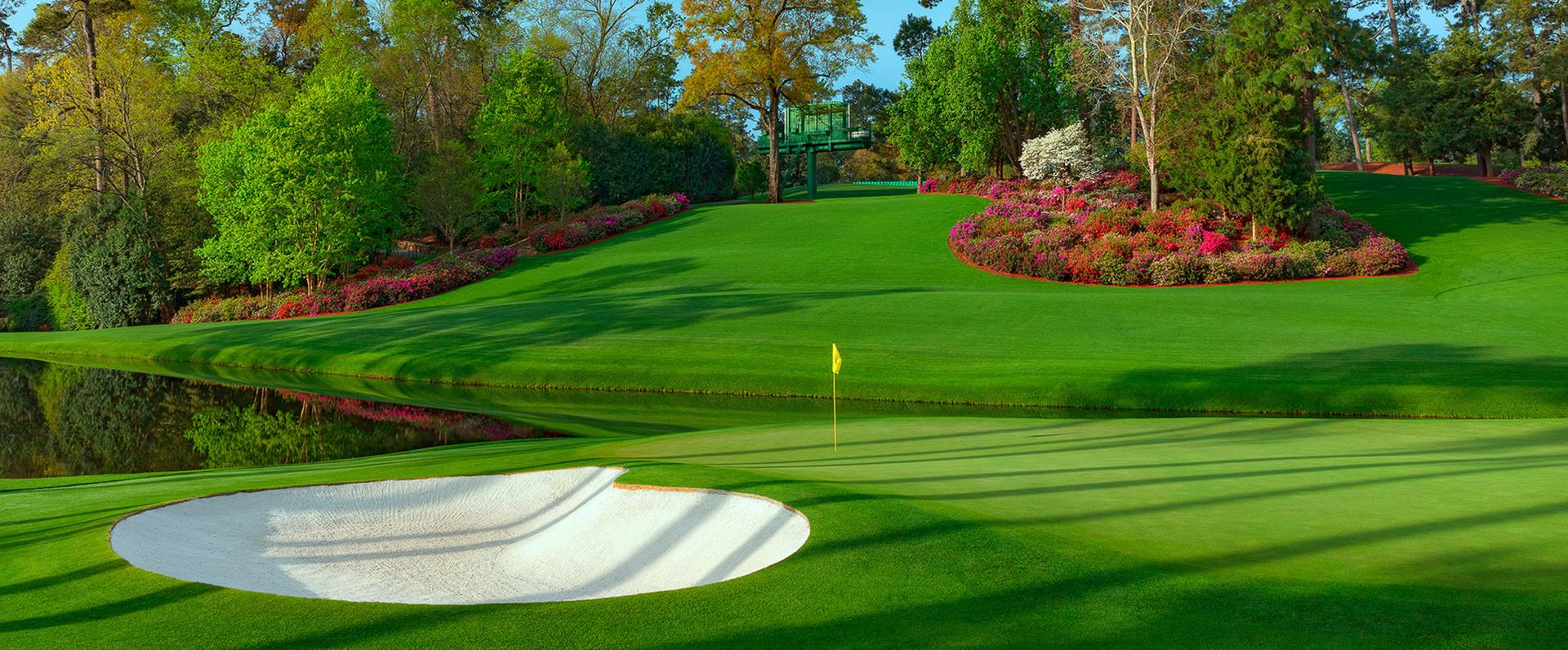 Lush green with a water hazard behind, azaelias in the background