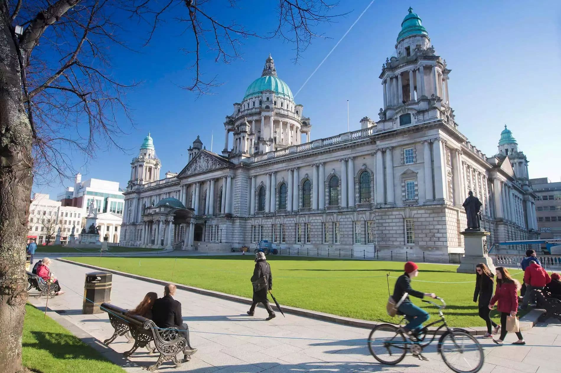 Cyclists passing Belfast City Hall on a sunny afternoon