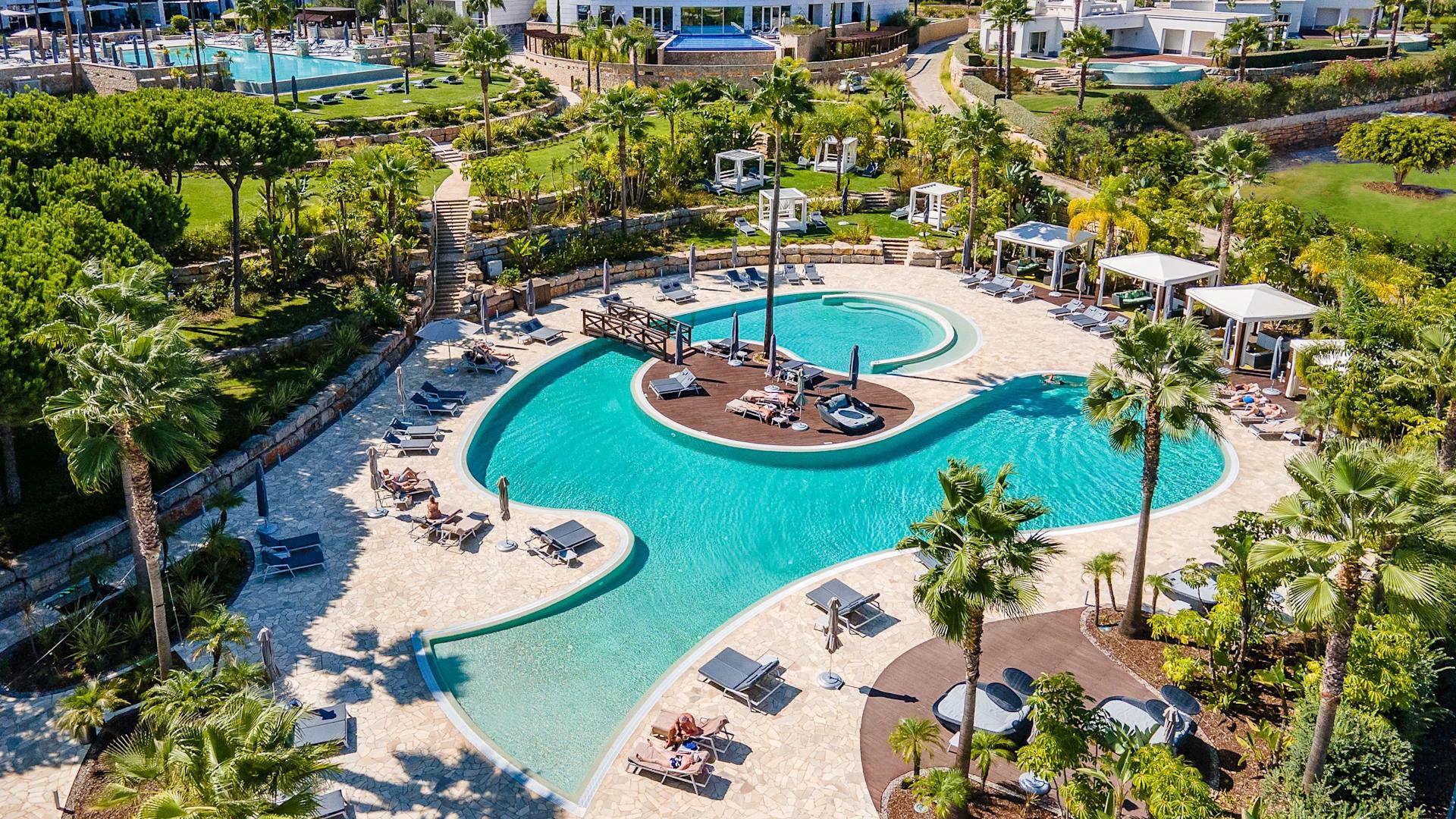 Overhead view of the Conrad Algarve's outdoor swimming pool surrounded by sunbeds and palm trees