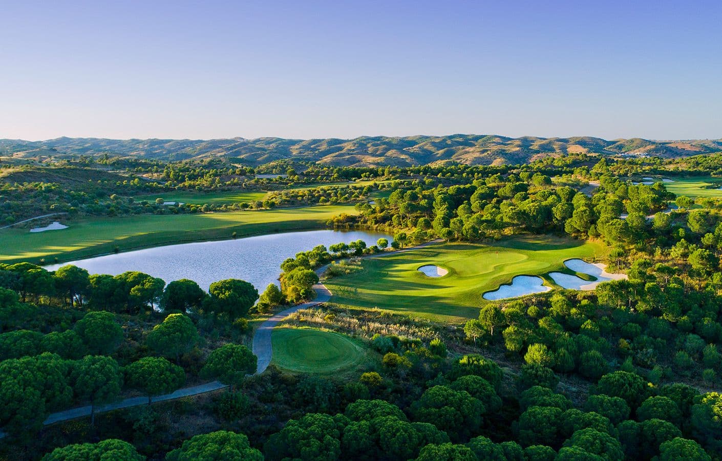 Aerial view of a smooth green surrounded by bunkers under clear blue skies
