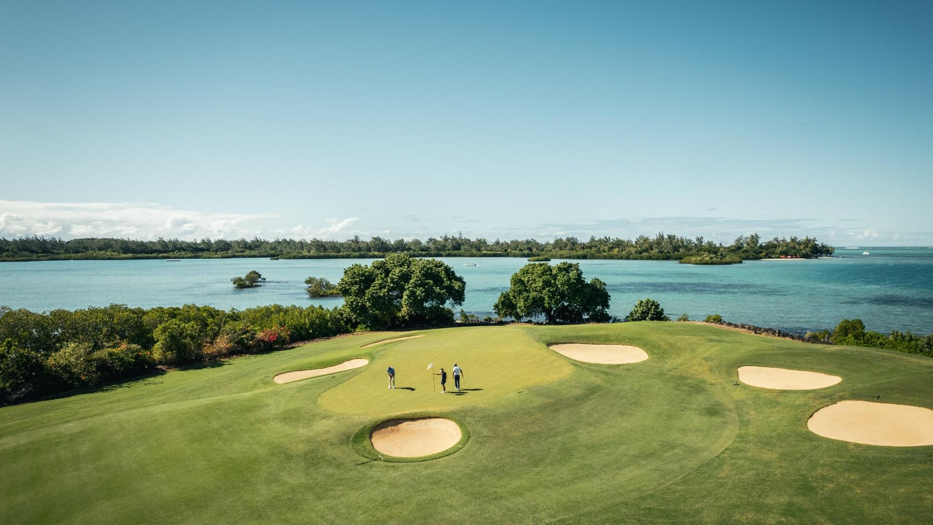 Green on the Els Course with bunkers around and the Indian Ocean behind