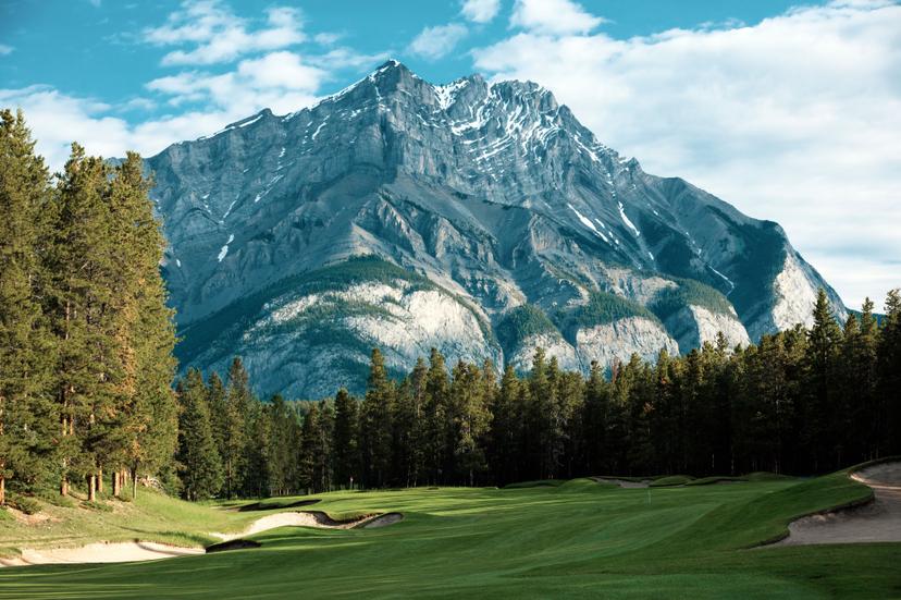 An ice topped mountain towering over a wide fairway leading to a smooth green on the course