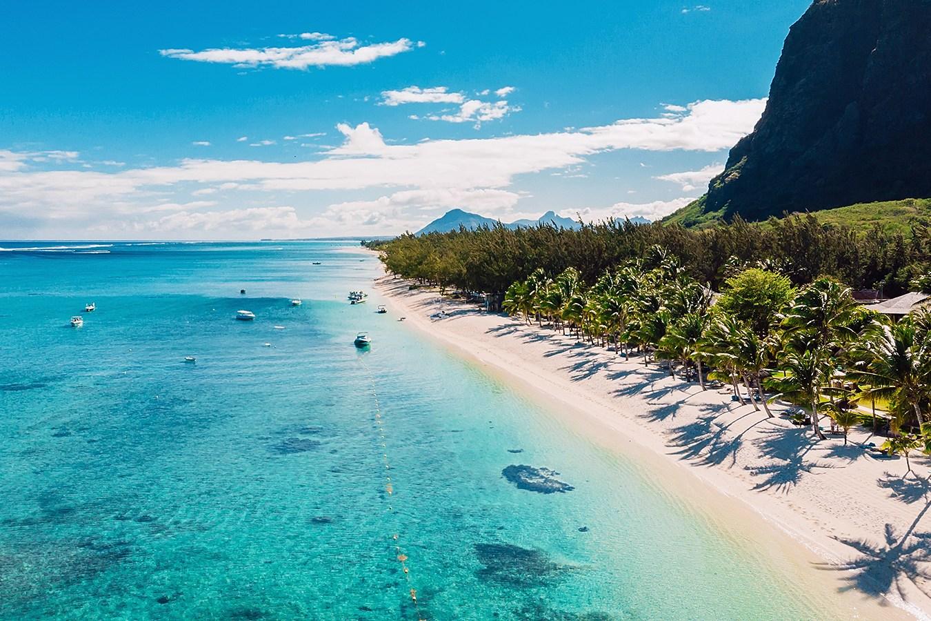 View of a bay in Mauritius with white sand, turquoise water and boats present