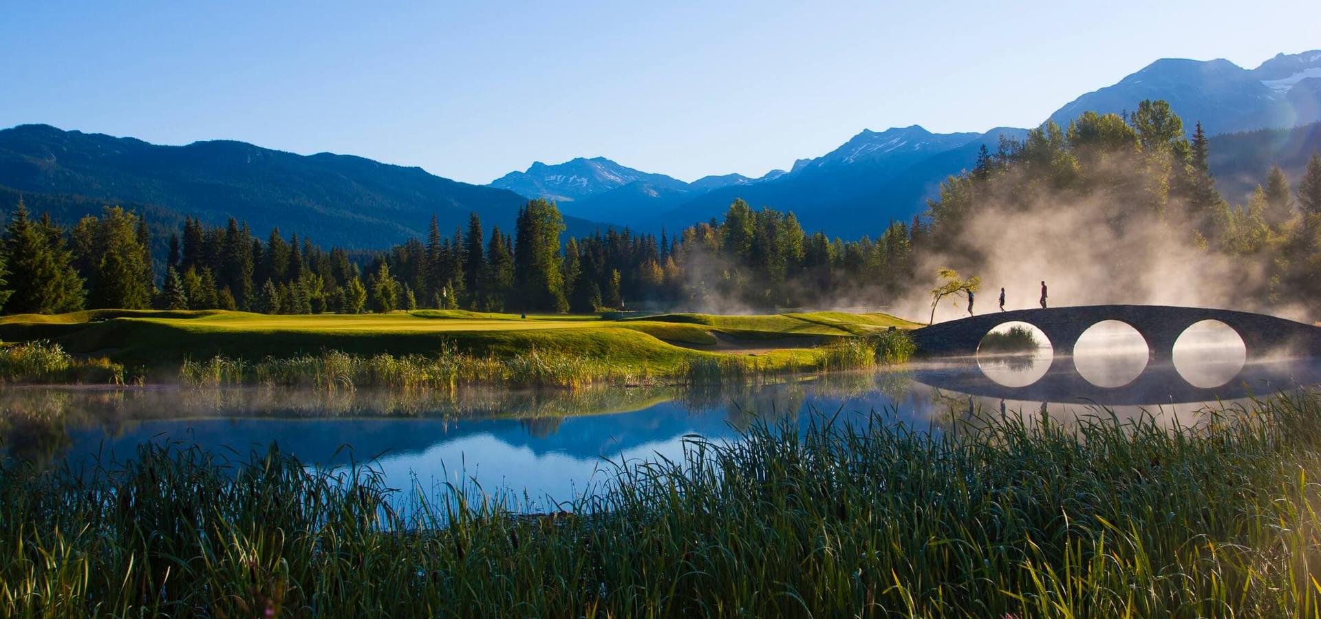A bridge to navigate the water hazard o the course with mountains views in the distance