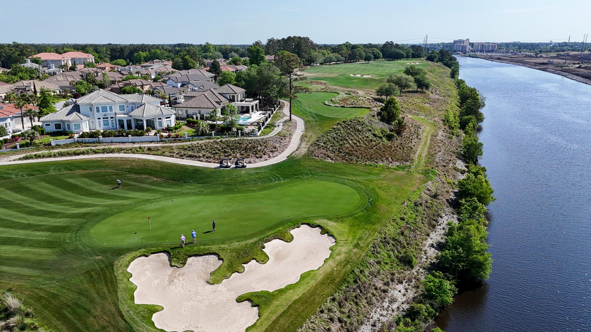 Overhead view of a large sand bunker next to a manicured green