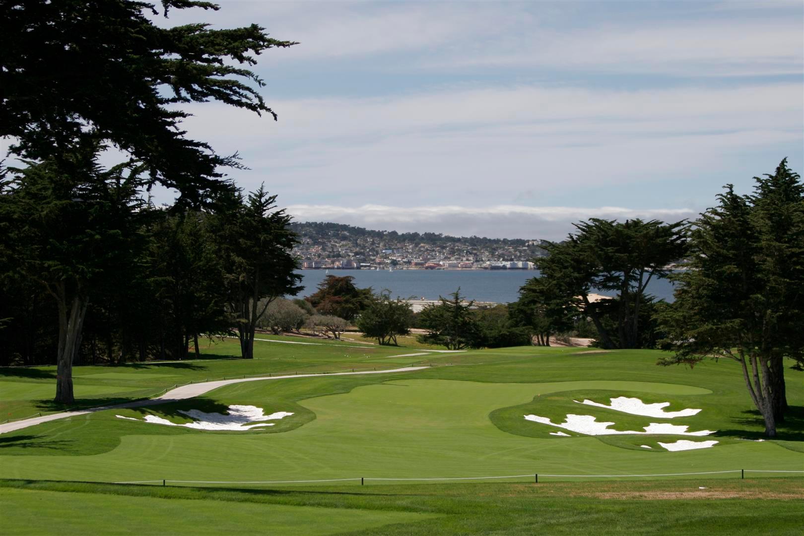 A winding fairway nestled with sand bunkers with coastal views from the course