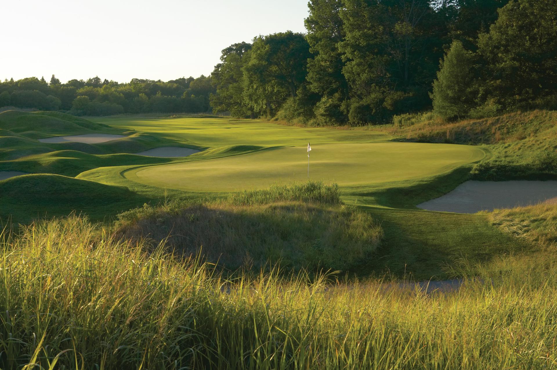 Panoramic view of a wide fairway leading to a smooth green surrounded by sand bunkers