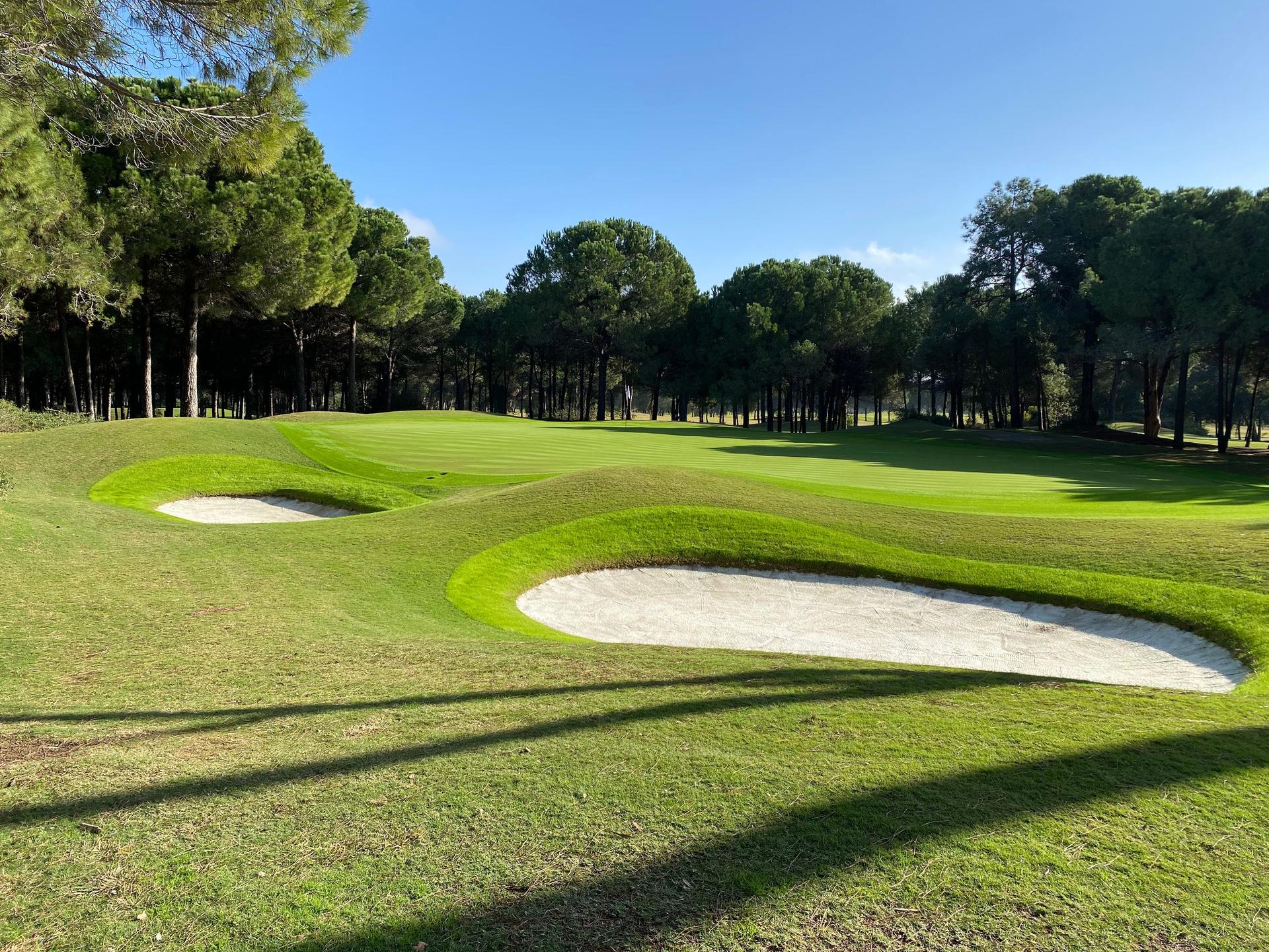 Panoramic view of a smooth green surrounded by sand bunkers at The Pasha Course
