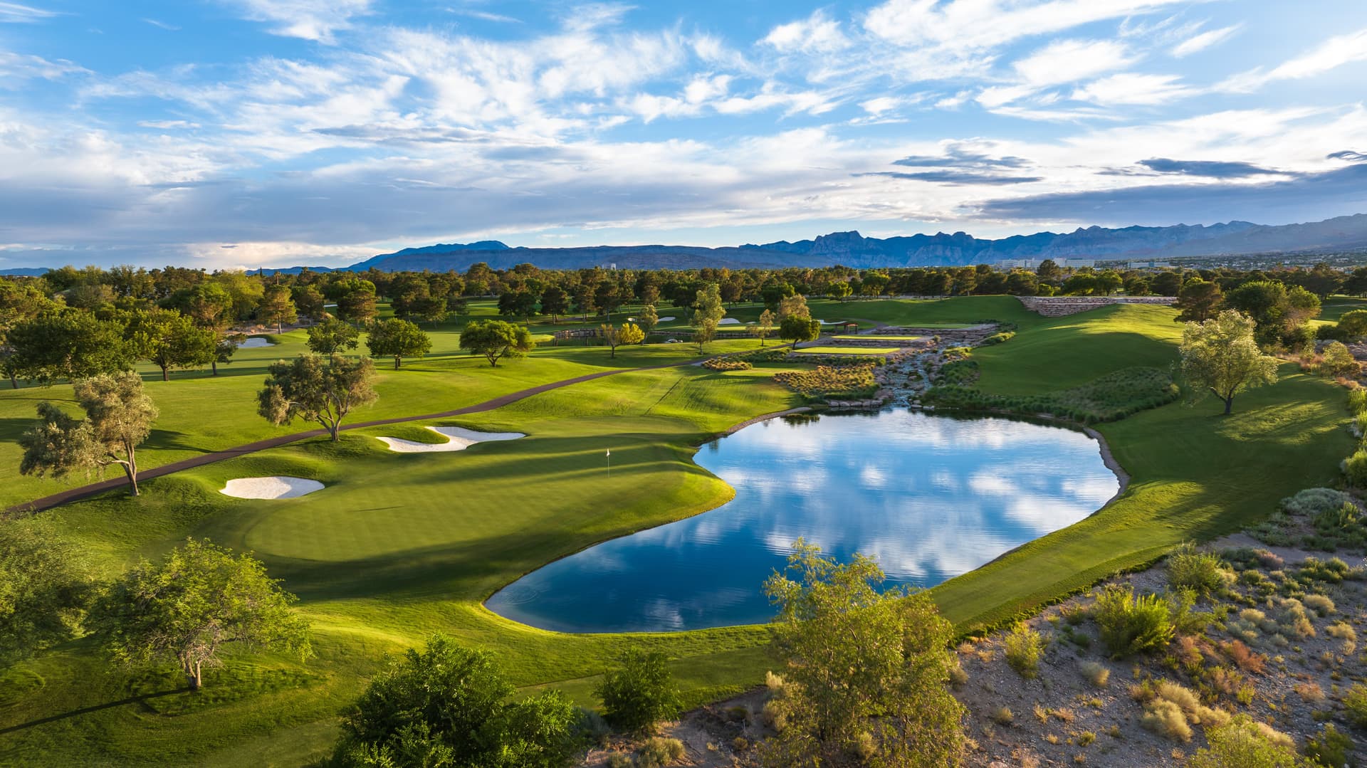 Overhead view of a green sandwiched between a sand bunker and a water hazard